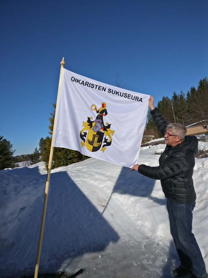 Seuran puheenjohtaja Erkki Oikarinen esittelee sukuseuran uuden banderollin.